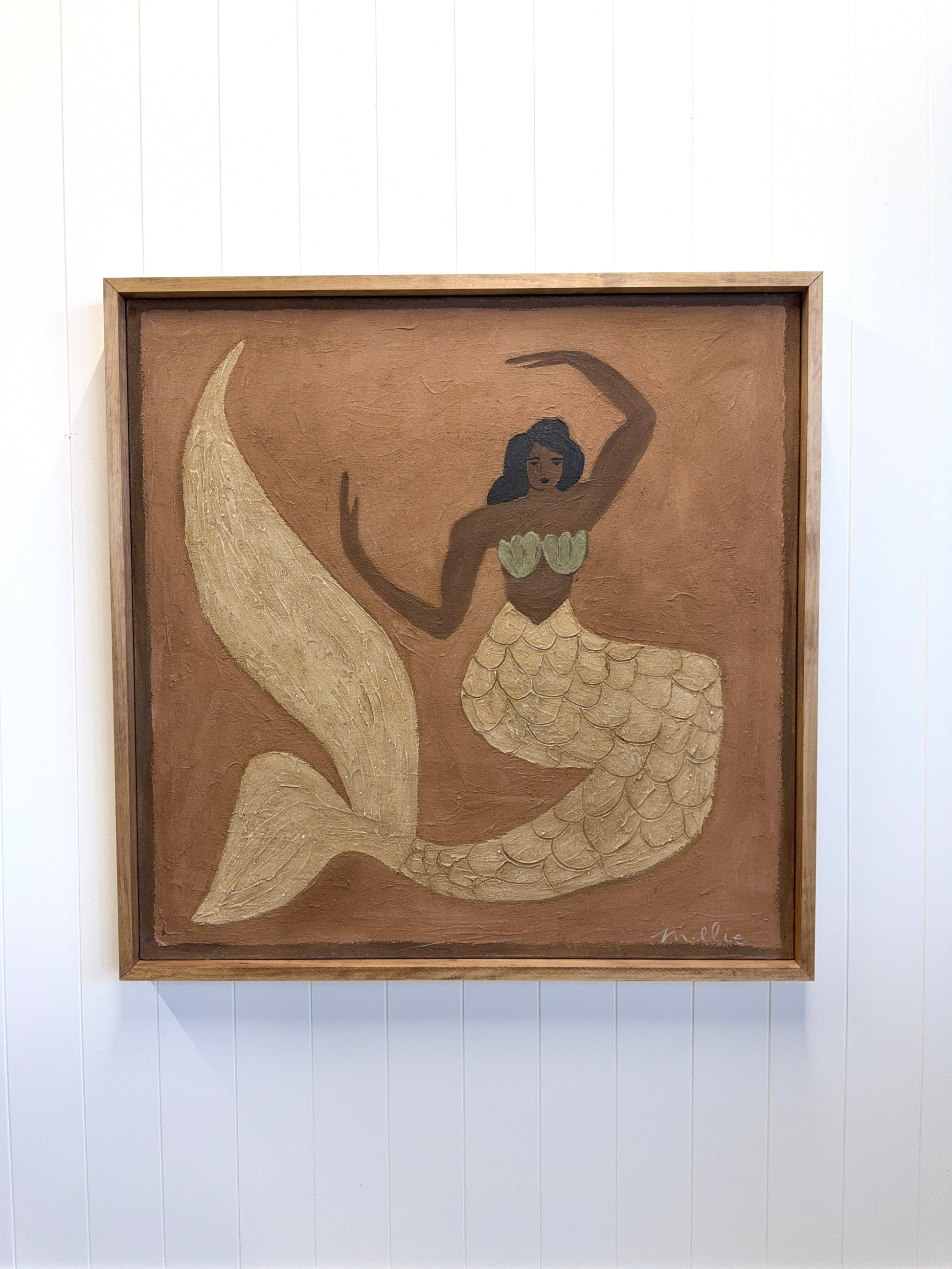 Framed artwork of a mermaid on a white wall